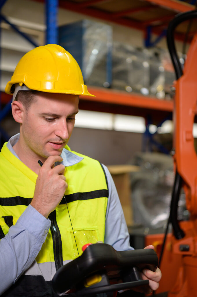 a male worker is controlling a welding robot. by using forcing w